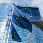 European Union flags waving outside glass building