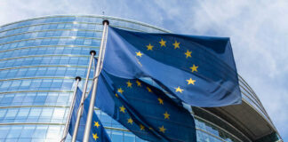 European Union flags waving outside glass building