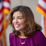 Smiling woman in a purple dress with flags behind