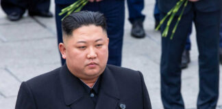 Person in dark coat standing on gray pavement