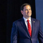 Man in suit and red tie on stage