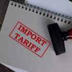 Import tariff stamp on notebook and wooden table