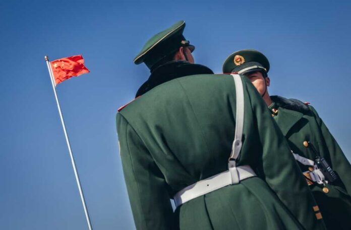 Two Chinese soldiers in uniform standing near the national flag
