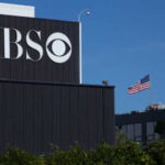 CBS Alters Hegseth’s Words – Outrage Ensues CBS sign on building, American flag in background.