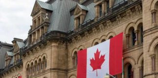Historic building with large Canadian flags displayed outside