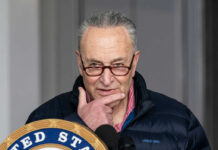 Man speaking at a podium with a thoughtful expression