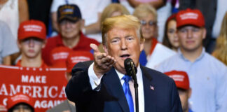 Man speaking at rally with crowd behind him