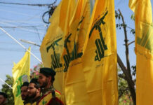 Beirut Shockwave: Hezbollah Powerbroker Targeted Men in military attire with yellow flags outdoors
