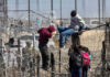 Metering Madness: The Fight Over Border Control People climbing barbed wire fence wearing backpacks and hoodies