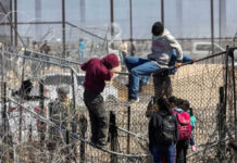 Metering Madness: The Fight Over Border Control People climbing barbed wire fence wearing backpacks and hoodies
