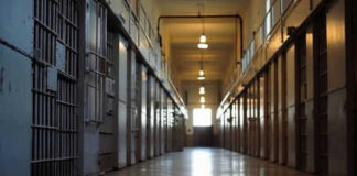 Empty prison corridor with metal cell doors visible