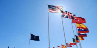 Flags of multiple countries against blue sky