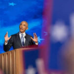 Executive Pay Gap Exposed at $850M Obama Center Man speaking at podium with blue starry background