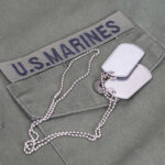 Ex-Marine’s Shocking Flag Stunt Sparks Fury Close-up of a U.S. Marines uniform with dog tags