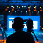 Cameramen preparing for a video shoot on a brightly lit stage