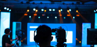Cameramen preparing for a video shoot on a brightly lit stage