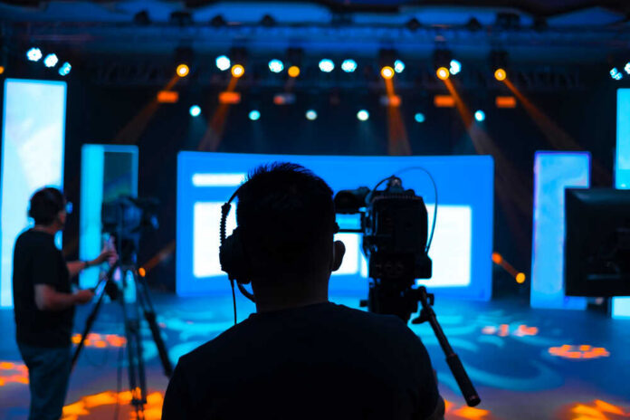 Cameramen preparing for a video shoot on a brightly lit stage