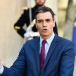 AI Overreach: Spain’s New Tool Sparks Free Speech Concerns A government official delivering a speech outdoors with flags in the background
