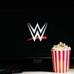A striped popcorn bucket in front of a screen displaying the WWE logo