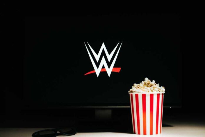 A striped popcorn bucket in front of a screen displaying the WWE logo