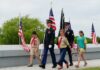Children and military personnel participating in a memorial ceremony with flags