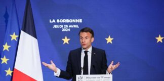 Emmanuel Macron delivering a speech at La Sorbonne with flags in the background