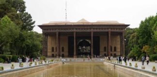 A historical building surrounded by greenery and a reflection pool