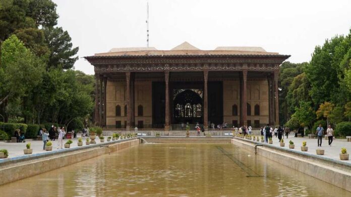A historical building surrounded by greenery and a reflection pool