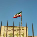 Beirut Blast: Iranian Diplomats Targeted Iranian flag waving above a government building against a blue sky