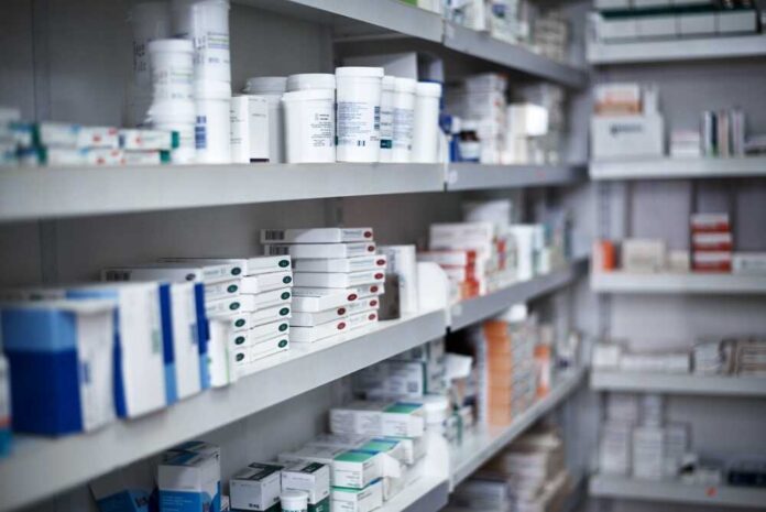 Shelves filled with various medication boxes and containers in a pharmacy