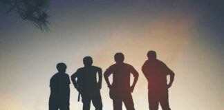 Silhouetted figures of four friends standing against a sunset