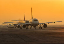 Airplanes lined up on a runway during sunset
