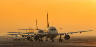 Airplanes lined up on a runway during sunset