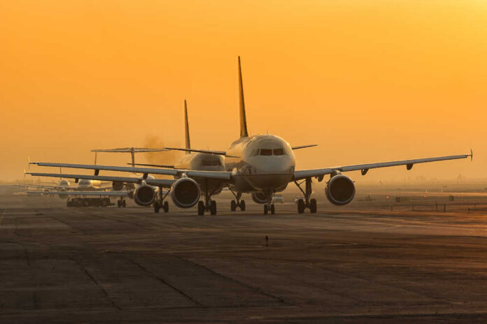 Airplanes lined up on a runway during sunset