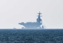 An aircraft carrier partially obscured by fog on the ocean