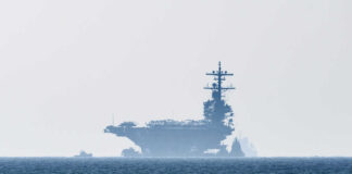 An aircraft carrier partially obscured by fog on the ocean