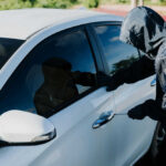 Person in hoodie attempting to break into car.