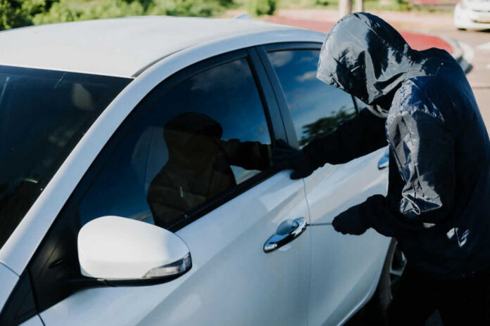 Person in hoodie attempting to break into car.