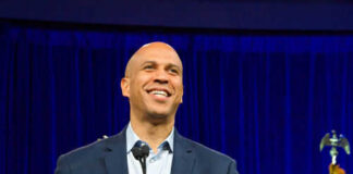 Man smiling at podium with American flag behind