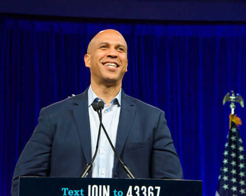 Man smiling at podium with American flag behind