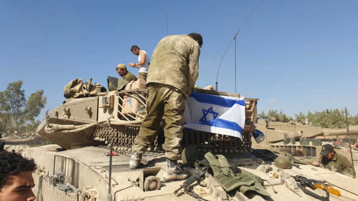 Soldiers on tank with Israeli flag in open field