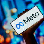 Hand holding phone displaying Meta logo