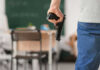 Person holding handgun in classroom setting
