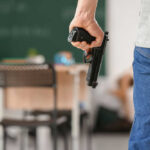 Person holding handgun in classroom setting
