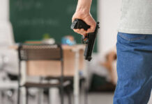 Person holding handgun in classroom setting