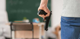 Person holding handgun in classroom setting