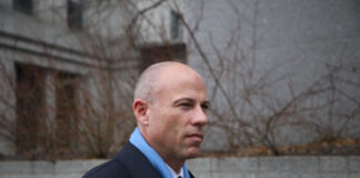 A man in business attire walking in an urban area with a serious expression