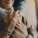 An elderly man being embraced by a younger person, showcasing a moment of affection