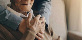 An elderly man being embraced by a younger person, showcasing a moment of affection