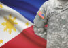 A soldier in a U.S. Army uniform with the Philippine flag in the background